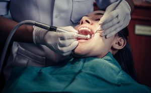 dentista esta limpiando los dientes de una señorita en el consultorio